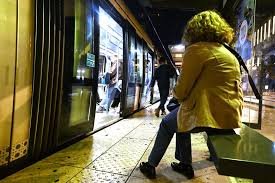 Une femme seule sur un quai de tramway la nuit — la vulnérabilité d'un inconnu dans l'espace public