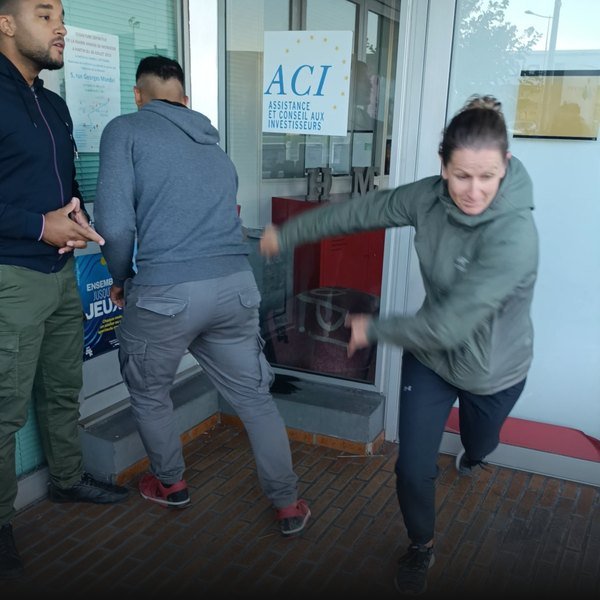 Mise en situation de self-défense dans un hall : une élève repousse un agresseur